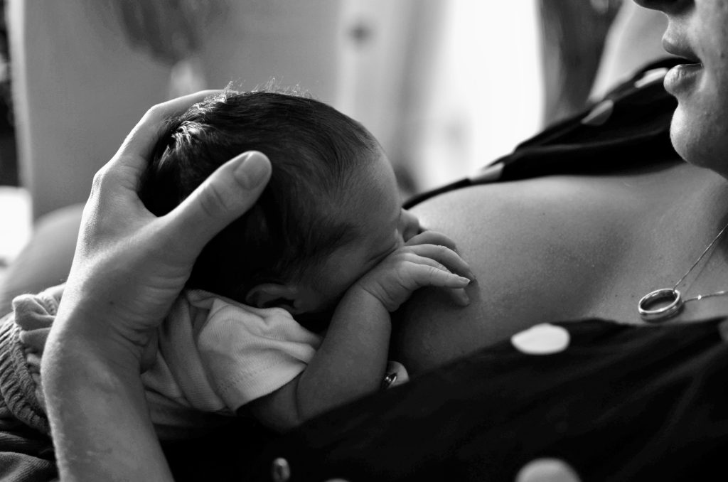 Close-up of mother breastfeeding newborn in "laid-back" breastfeeding position.