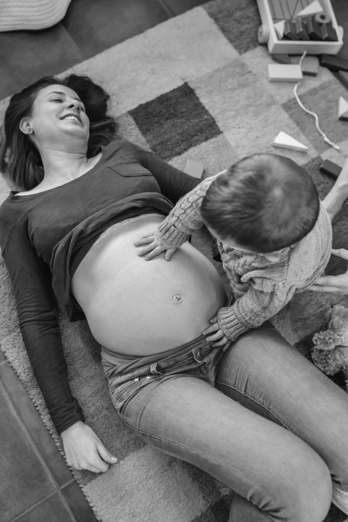 Toddler caressing belly of its pregnant mother.