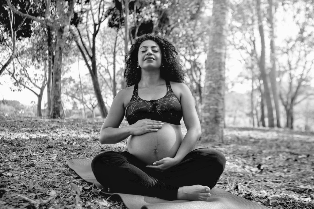 Pregnant Afro-Latina woman doing yoga outdoors on a sunny day